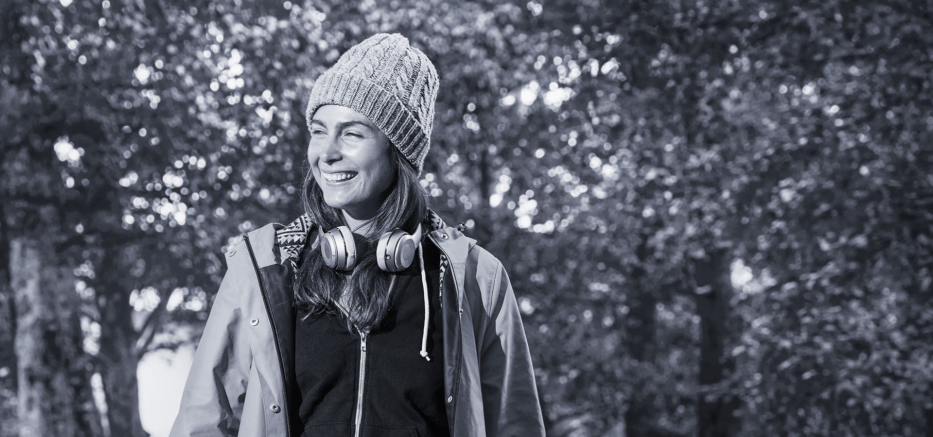 Student walking in woods wearing headphones