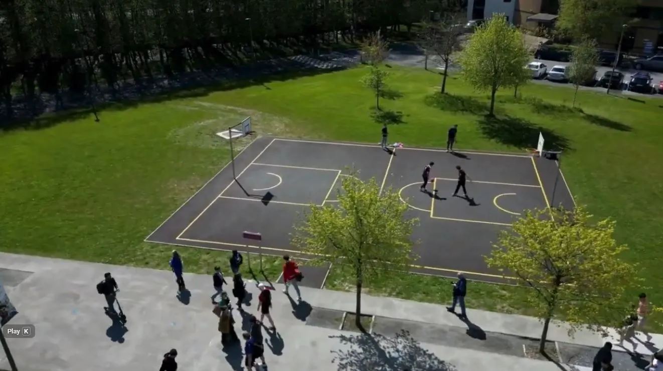 arial shot of a basketball course on campus, surrounded by lush green grass and trees