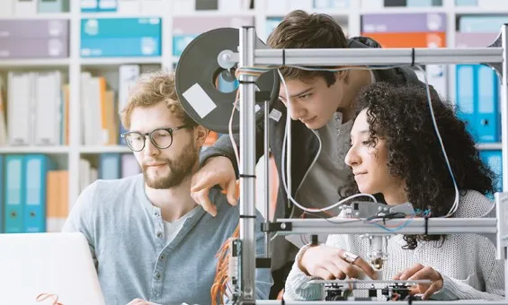 One female and two males students in a lab, looking at a laptop